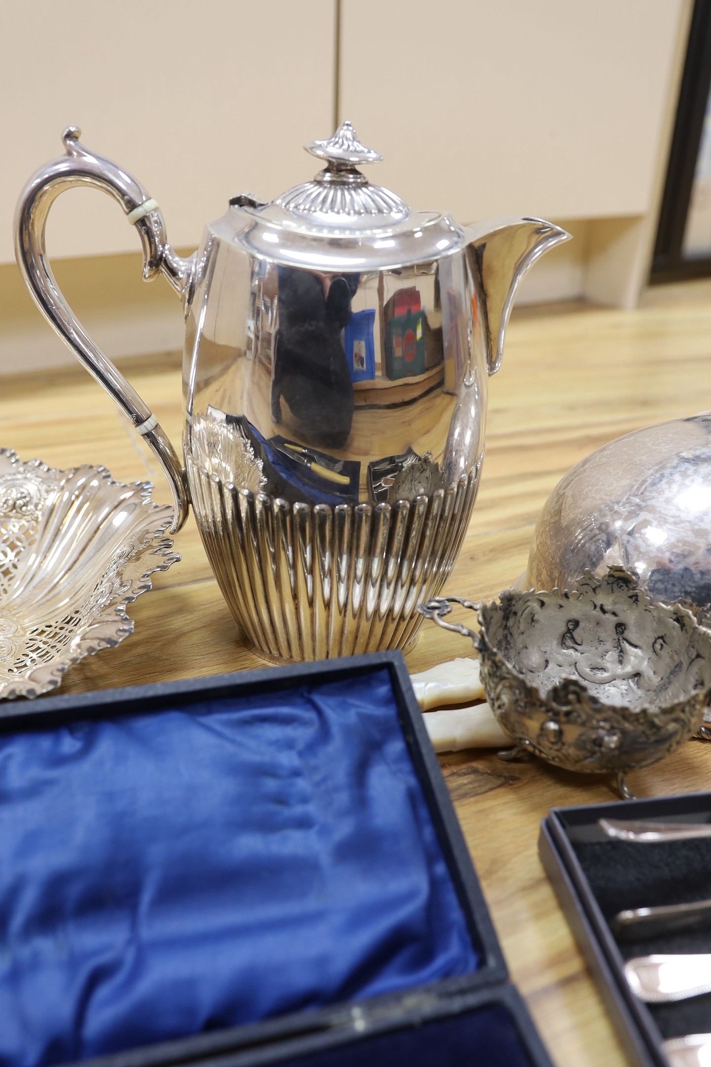 A cast white metal bowl and a collectio of plated items including a hot water pot, meat cover, cased flatware, etc.